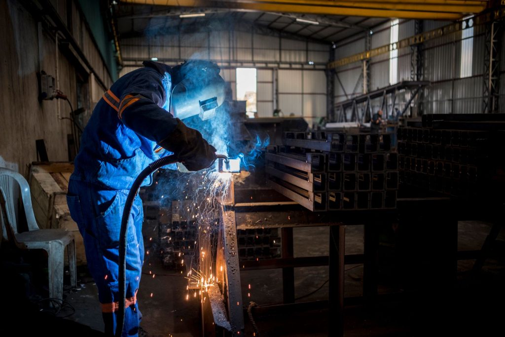 Schweißer in blauer Arbeitskleidung in einer Metallbau-Werkstatt