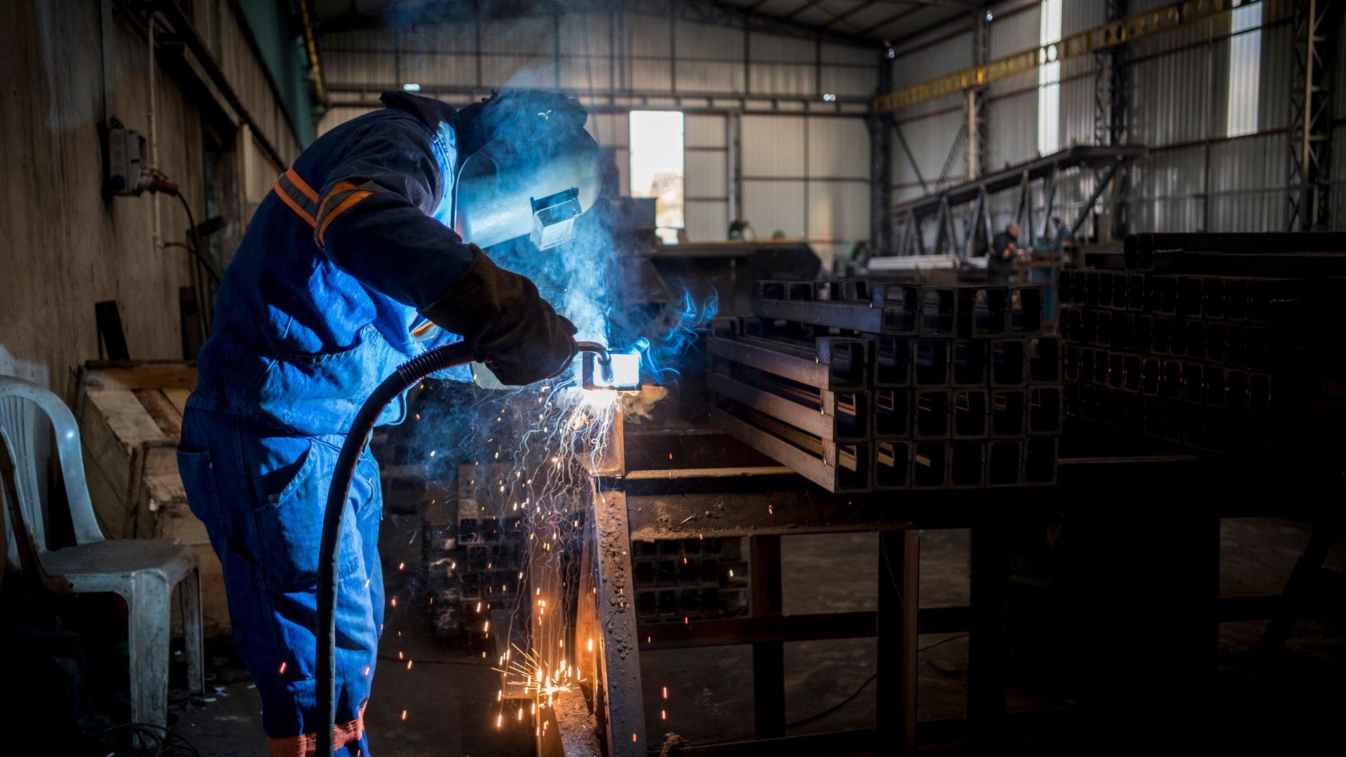 Schweißer in blauer Arbeitskleidung in einer Metallbau-Werkstatt